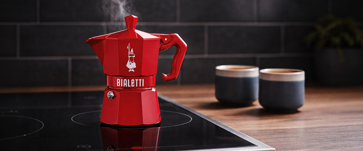 Bialetti Espressokocher auf schwarzem Herd mit aufsteigendem Dampf