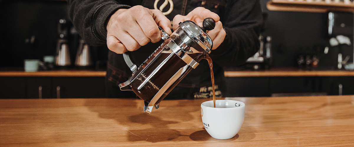 Frisch gebrühter French Press Kaffee wird in eine Tasse eingeschenkt