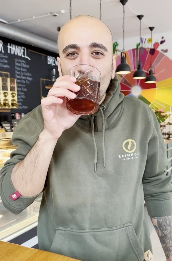 Barista Anton probiert einen frisch zubereiteten Cold Brew Kaffee auf Eis in der Reinholz Kaffeerösterei.