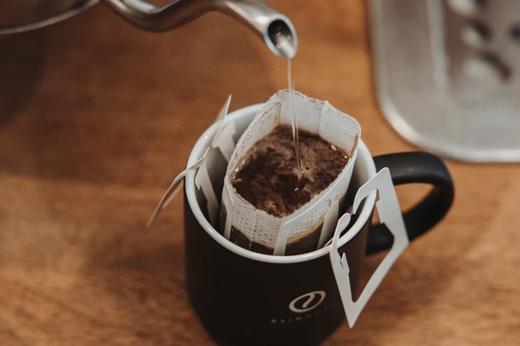 Kaffee im Drip Coffee Bag mit heißem Wasser anfeuchten