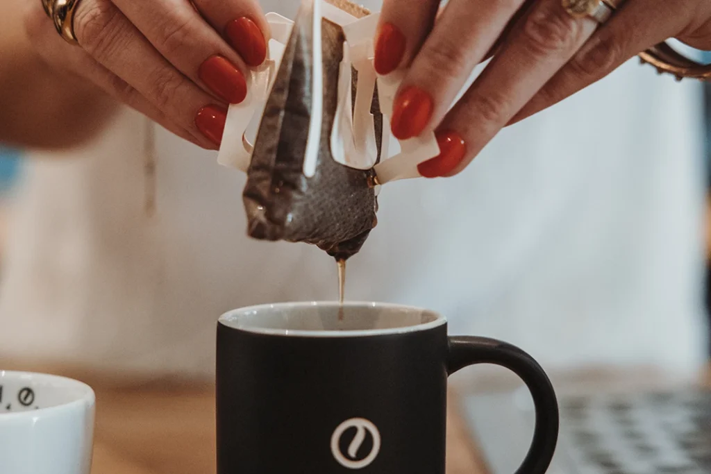 Fertig aufgebrühter Drip Coffee Bag wird aus der Tasse genommen