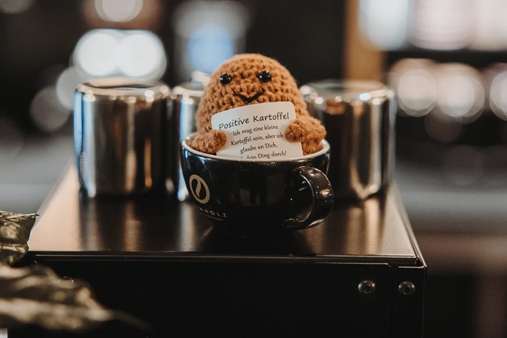 Das Reinholz Maskottchen „Positive Kartoffel“ in einer Kaffeetasse.