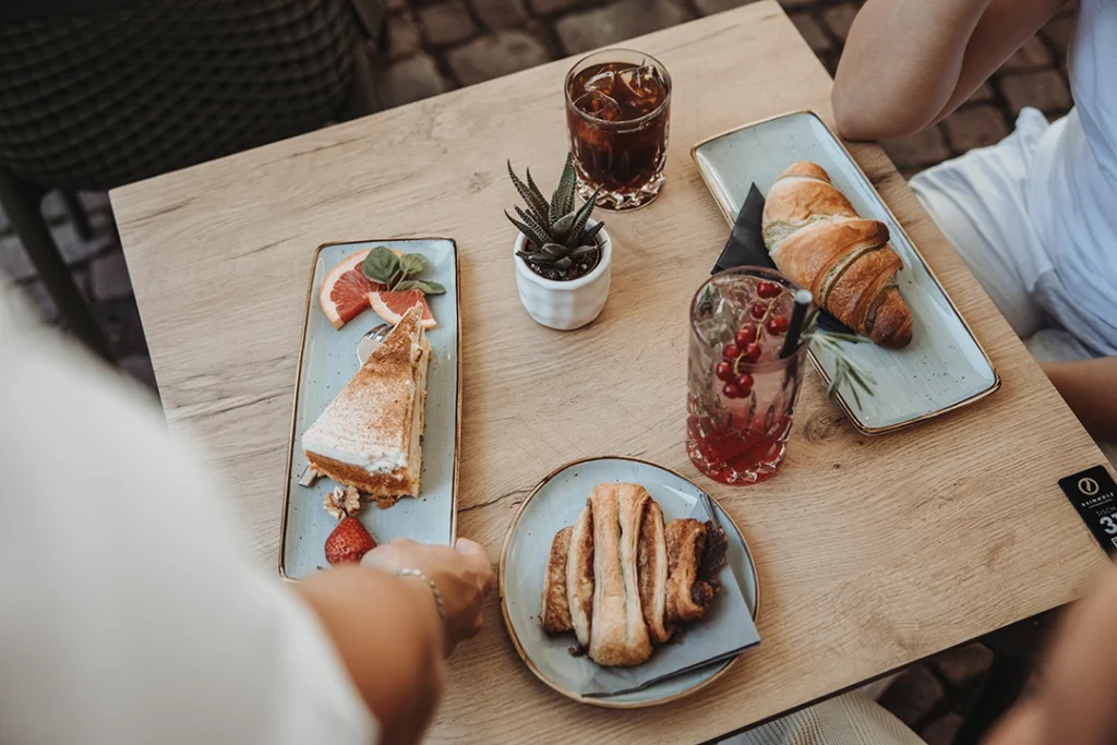Gäste genießen Kaffee, Kuchen und Frühstück auf der Terrasse des Reinholz Cafés am Buttermarkt in Fulda.