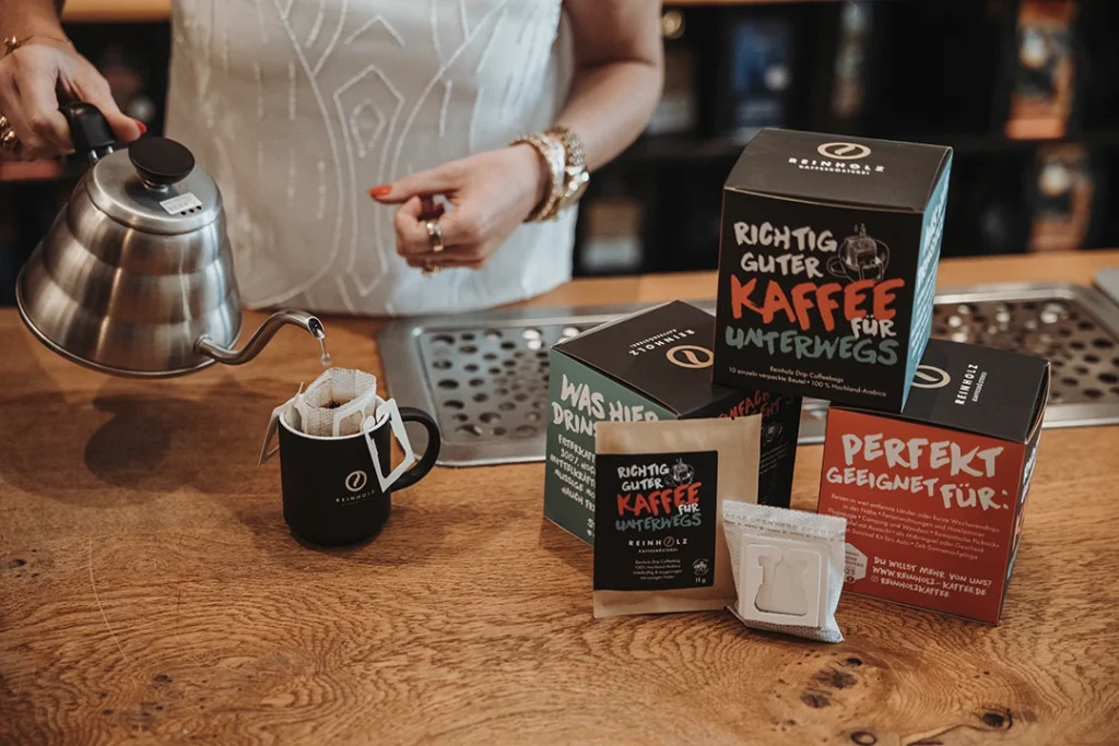 Reinholz Drip Coffee Bags mit schwarzer Kaffeetasse und Verpackung