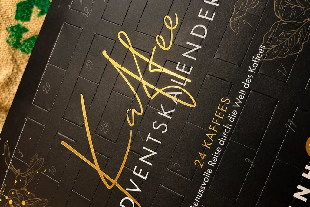 Detailansicht des Reinholz Kaffee-Adventskalenders 2026 mit goldener Schrift und Adventstürchen