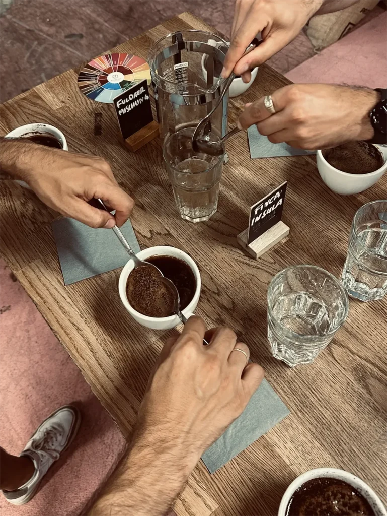 Kruste brechen: Nach dem Aufgießen bildet sich an der Oberfläche eine Schicht aus Kaffeepulver. Beim sogenannten „Break“ wird sie mit dem Löffel aufgebrochen – ein besonders aromatischer Moment beim Cupping.