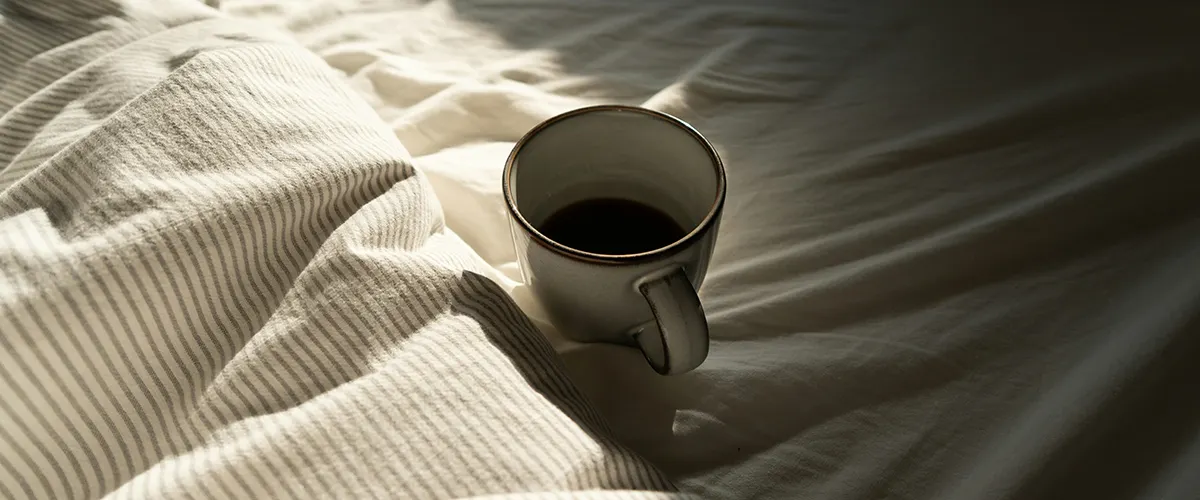Tasse Kaffee im Bett zum Thema Kaffee und Schlaf